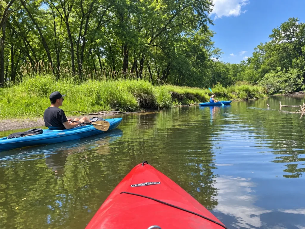 Kayakers paddling along a wooded stretch of the Kishwaukee River