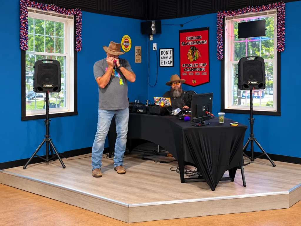Harmonica performer and sound operator on the indoor stage at Holiday Acres campground