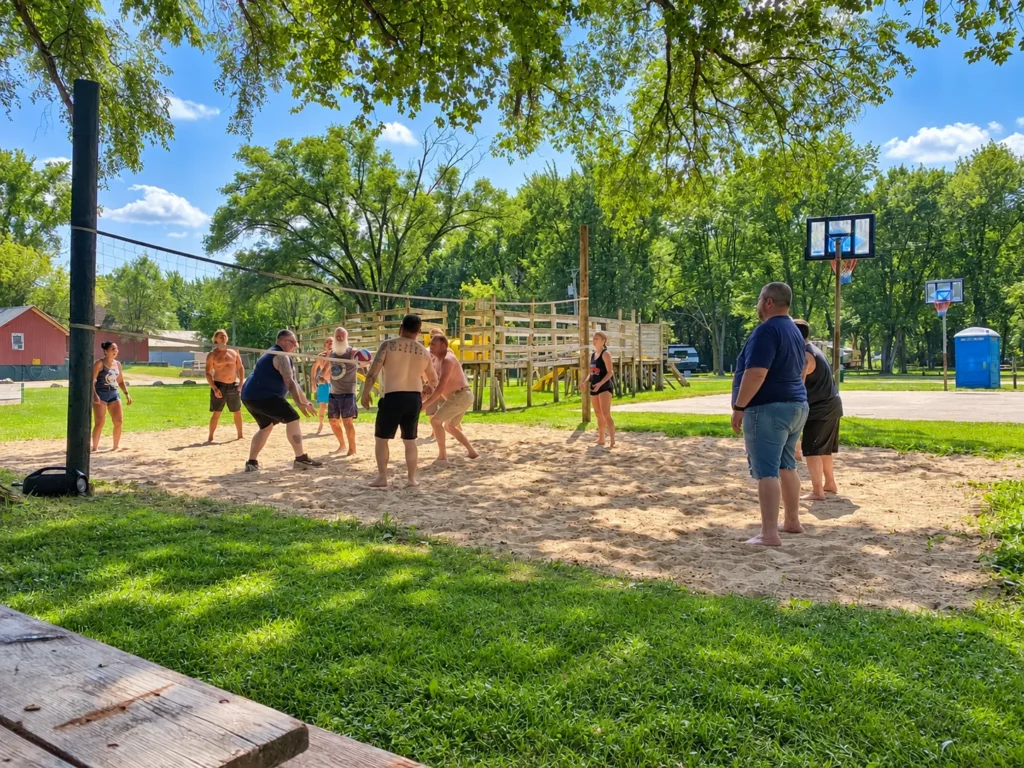 Campers playing sand volleyball beside the playground and basketball courts at Holiday Acres